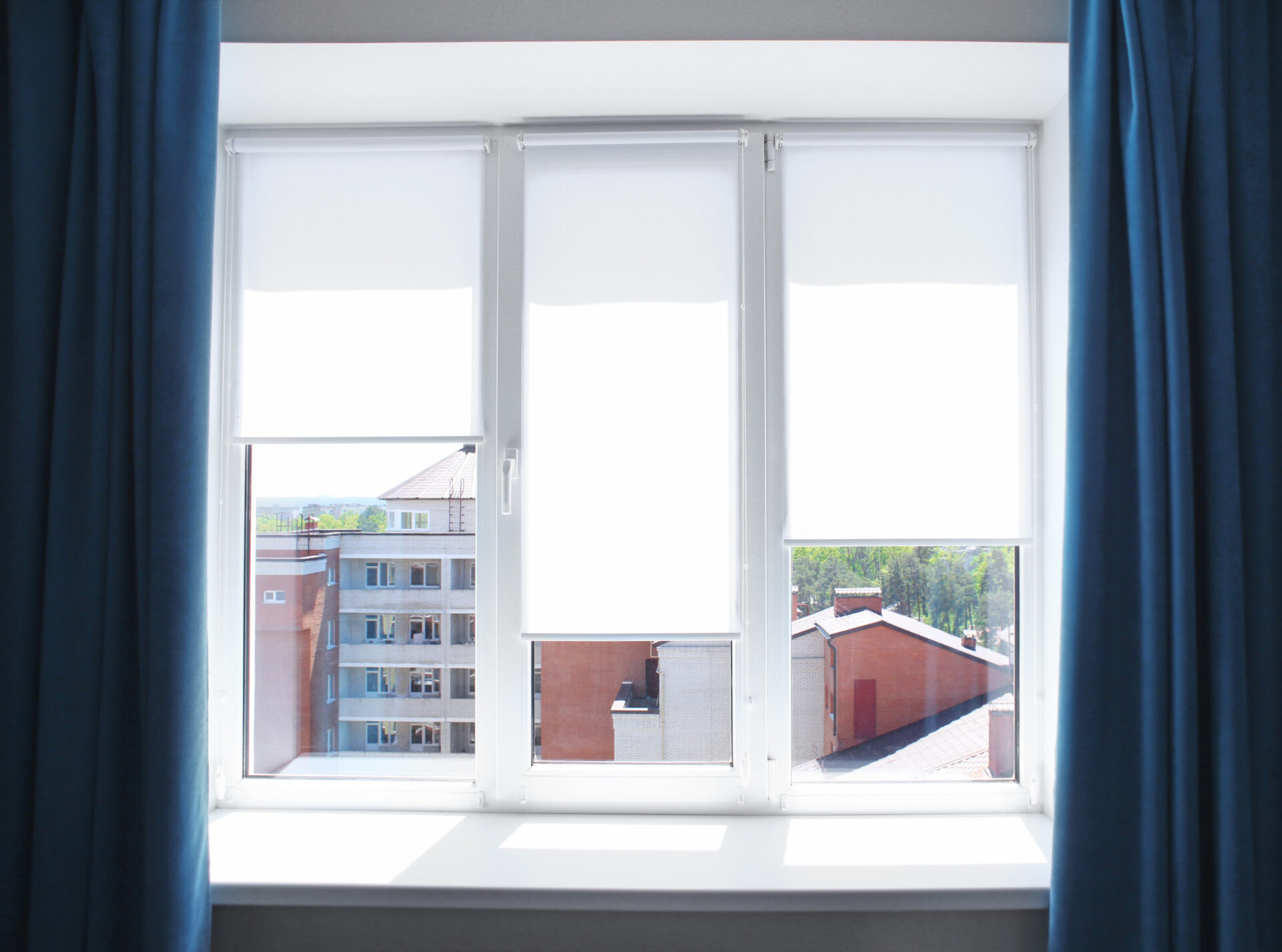 Modern white roller window shades in an apartment. Wholesale Blind Factory