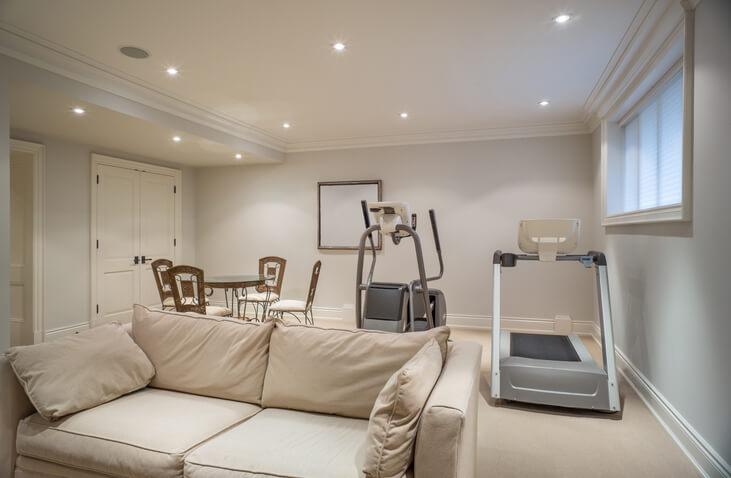 Light, airy basement space with couch and workout equipment